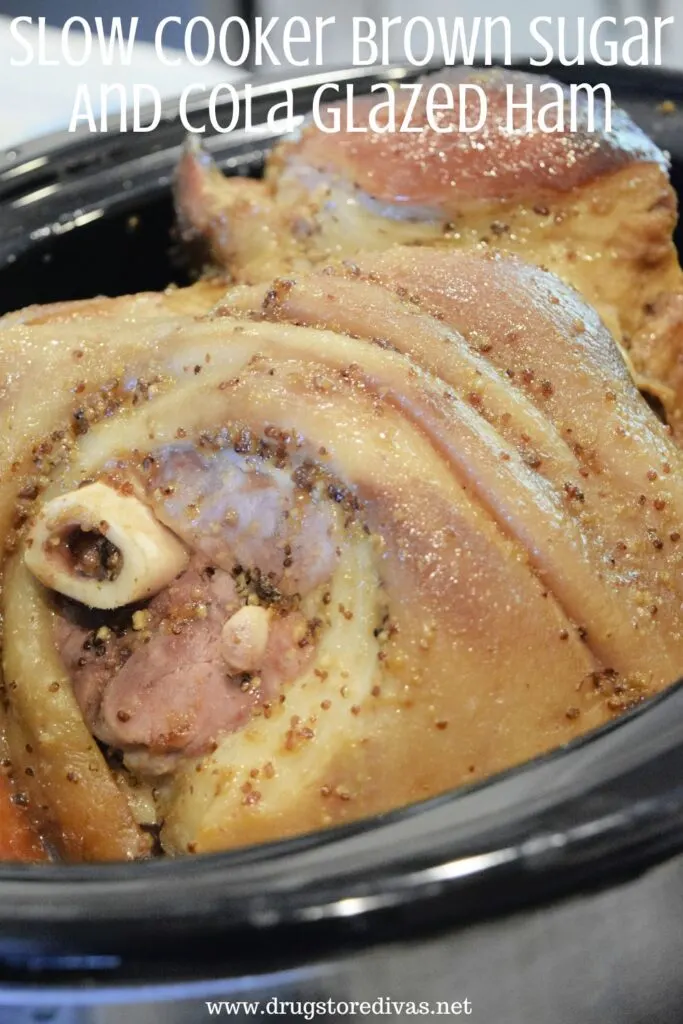 A fully cooked bone in ham in a slow cooker with the words "Slow Cooker Brown Sugar And Cola Glazed Ham" digitally written on top.