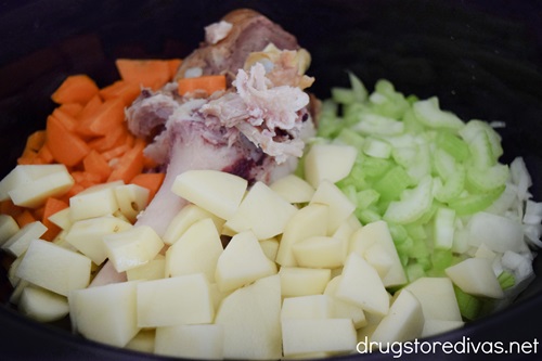 Chopper carrots, celery, and potatoes, plus a ham bone in a slow cooker.