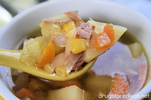 A yellow spoon with a spoonful of Slow Cooker Ham Bone Soup on it.