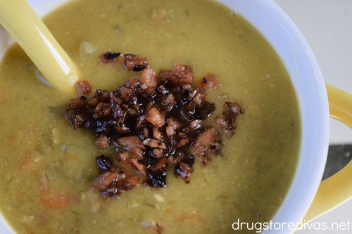 A bowl of slow cooker split pea soup with ham pieces on top.