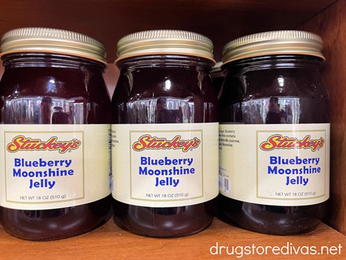 Three jars of Stuckey's blueberry moonshine jelly on a shelf.