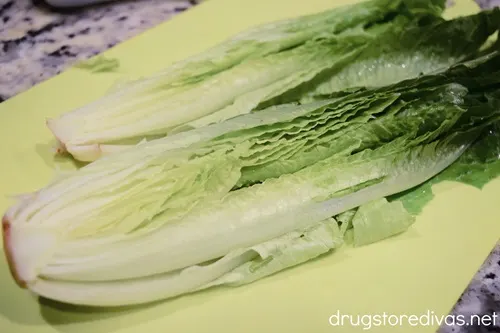 Romaine lettuce cut in half on a lime green cutting board.