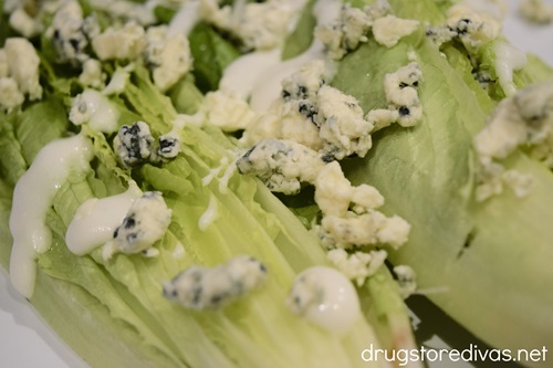 Bleu cheese crumbles and white salad dressing on romaine lettuce halves.