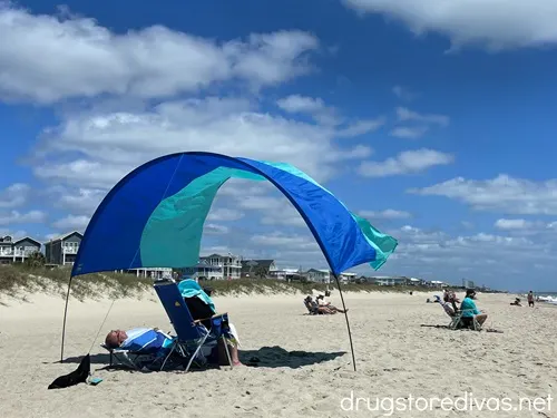 A two-toned blue beach shade above people on a beach.