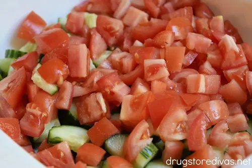 Cucumber and tomato pieces in a white bowl.