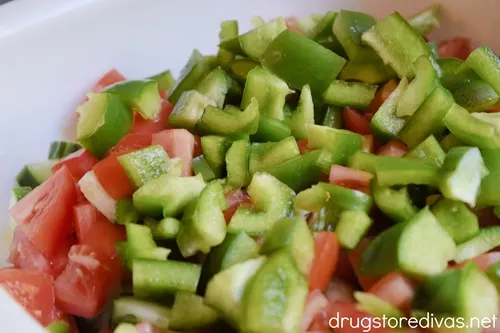 Cucumber, green pepper, and tomato pieces in a white bowl.