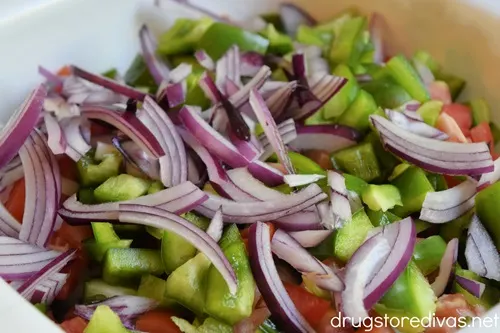 Cucumber, red onion, green pepper, and tomato pieces in a white bowl.