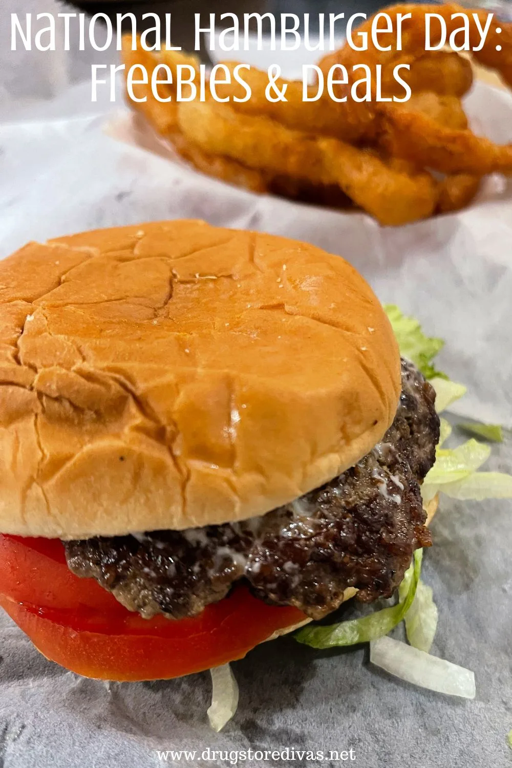 A burger with lettuce and tomato with onion rings in the back and the words 