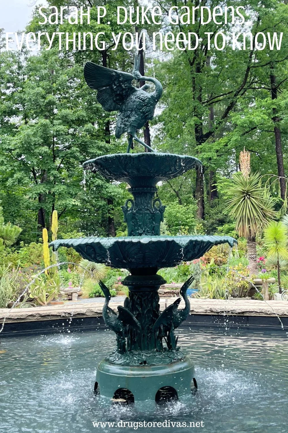 A stone fountain with two metal birds on top and the words 