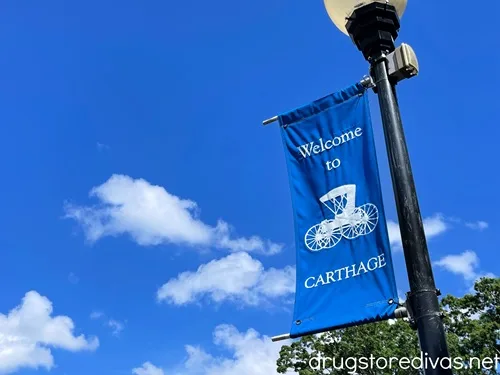 A blue Welcome To Carthage sign on a light post.