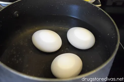 Three eggs in a bowl on water on a stove.