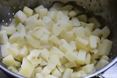 Cooked diced potatoes in a colander.