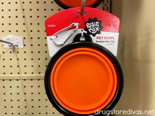 A red collapsible pet bowl hanging in a store.