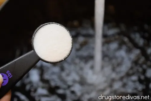 Salt being added to a pot that has water being poured into it.