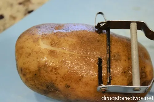 A peeler peeling a potato.