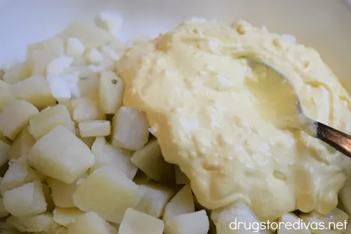 A creamy yellow egg yolk mixture on top of diced potatoes in a white bowl.