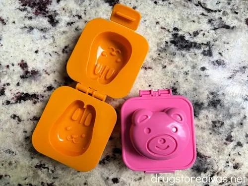 An orange bunny egg mold that's opened next to a pink pig egg mold that's closed.