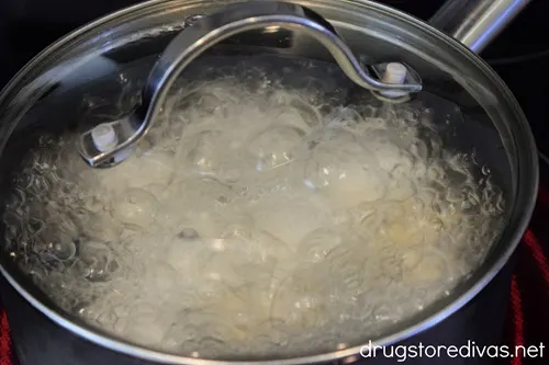 Hard boiled eggs in a pot of boiling water that has a lid on.