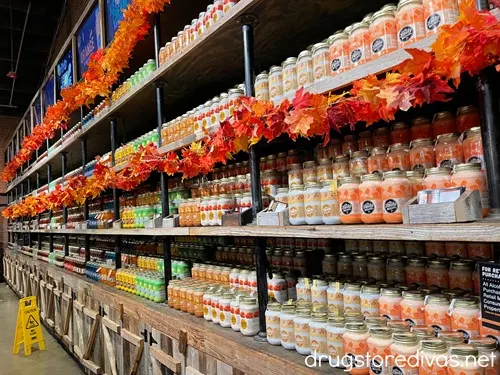 Mason jars filled with moonshine in rows across a wall with some fake fall leaves on the shelves at Ole Smoky Moonshine in Nashville.