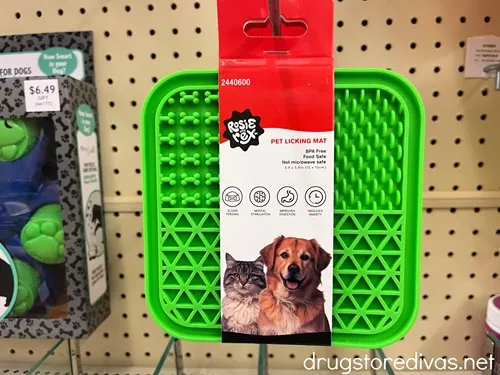 A green pet licking mat hanging on a peg in a store.