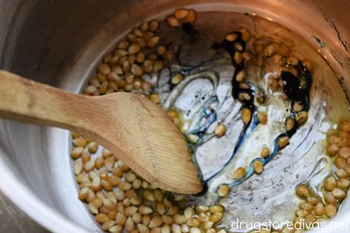 A bamboo spoon stirring popcorn that's dyed blue.