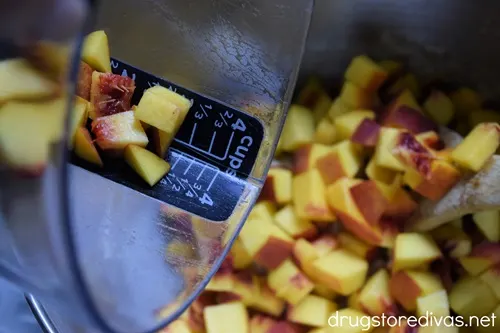 Cubes of fresh peaches in a measuring cup being poured into a bowl.
