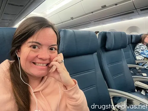 A woman in a pink sweatshirt sitting on an airplane.
