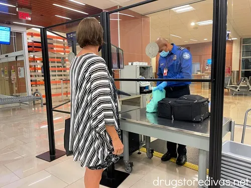 A woman getting luggage checked by a TSA agent at airport security.