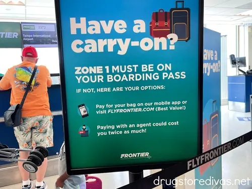 A sign at an airport telling about fees for a carry on bag.