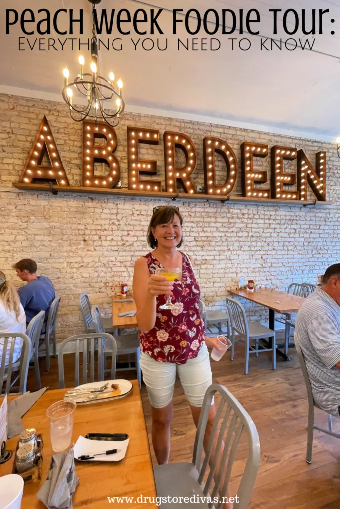 A woman holding a cocktail in a restaurant with the word ABERDEEN in lights above her with the words "Peach Week Foodie Tour: Everything you need to know" digitally written above her.