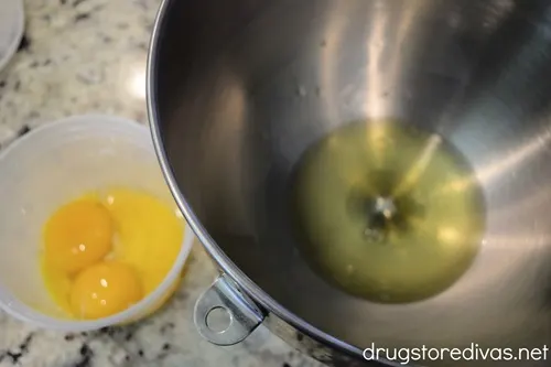 Eggs yolks in a clear container and egg whites in a silver bowl.
