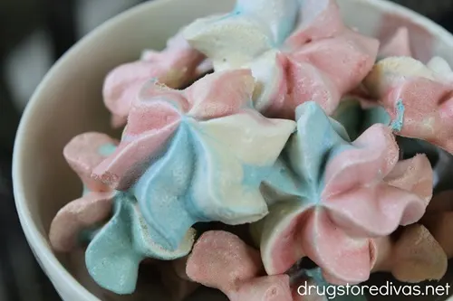 A white bowl filled with Red, White, And Blue Meringue cookies.