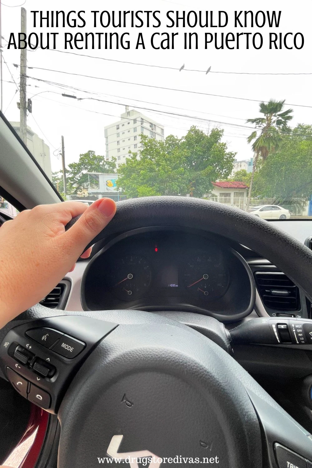 A hand on a steering wheel of a car with the words 