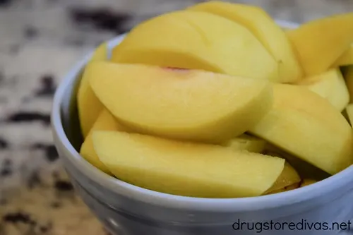Peach slices in a blue bowl.