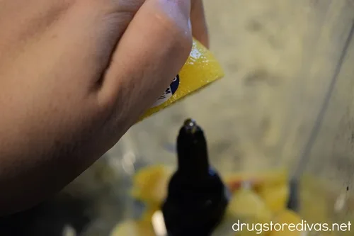 A hand squeezing a lemon into a blender of peaches.