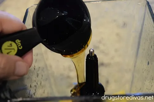 Honey in a measuring cup being poured into a blender.