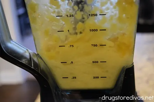 The side view of a blender filled with frozen peach lemonade.