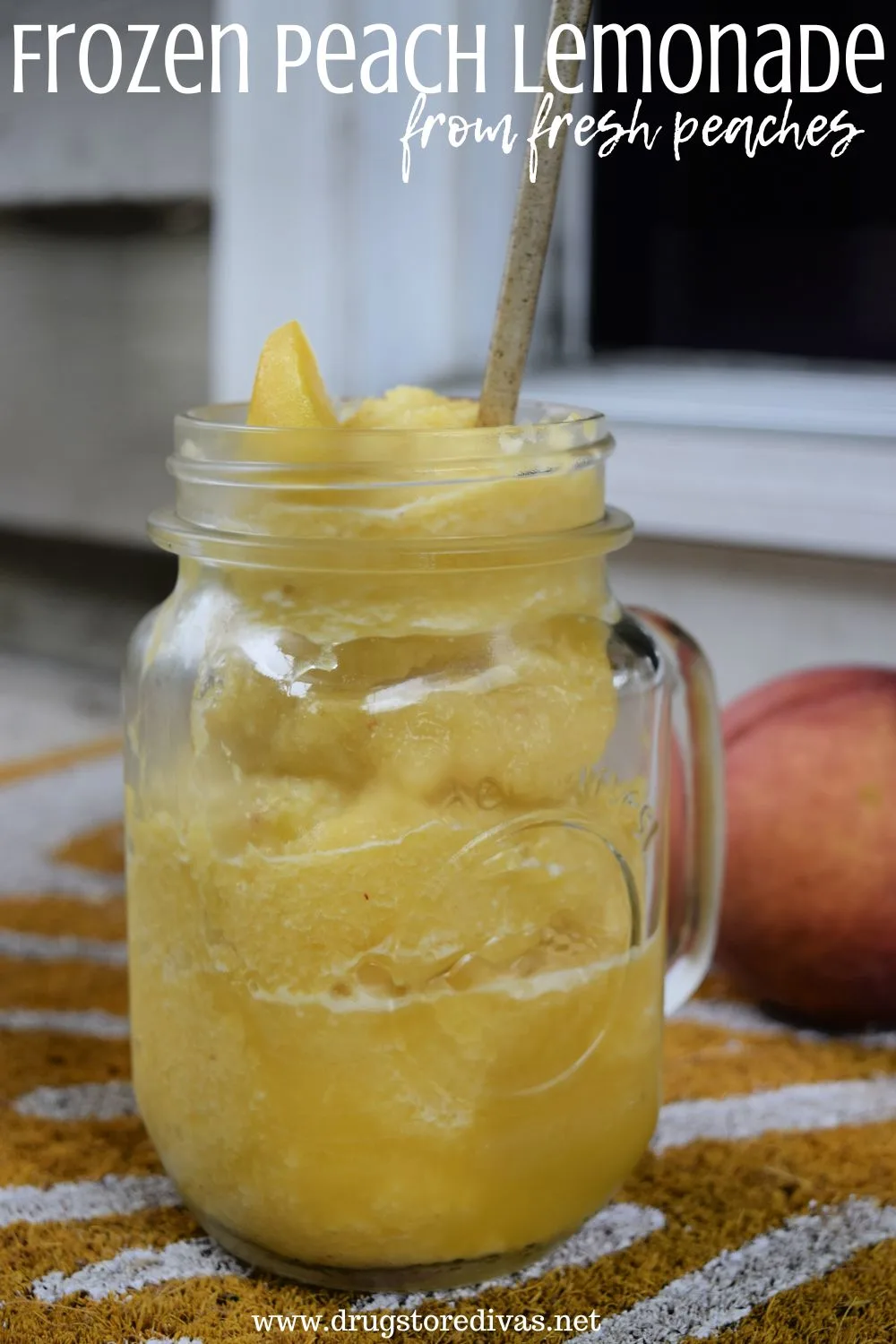 A mason jar with a handle filled with frozen peach lemonade and a peach behind it with the words 