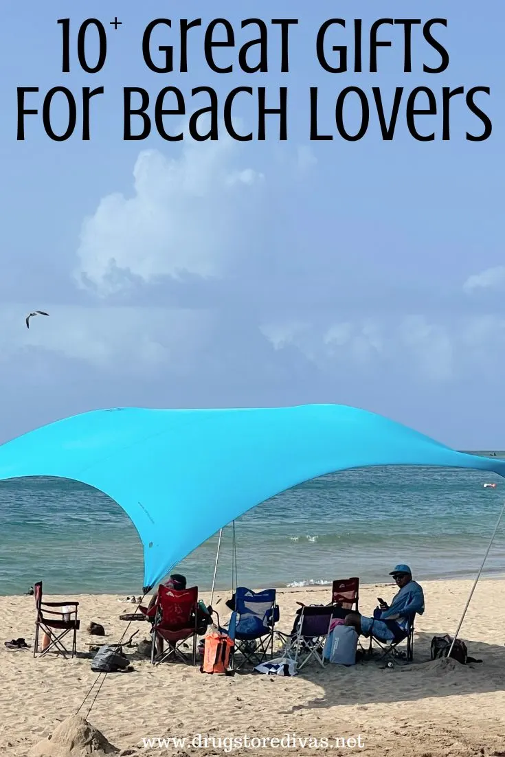 People on a beach under a blue beach shade with the words 