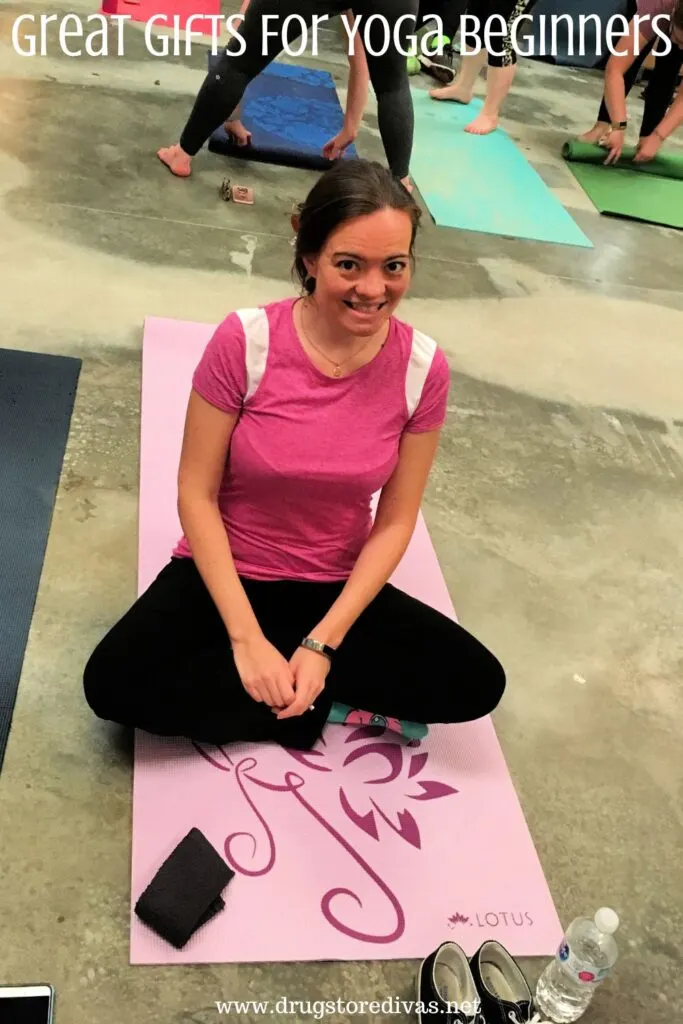 A woman in a pink top and black pants sitting on a yoga mat with the words "Great Gifts For Yoga Beginners" digitally written above her.