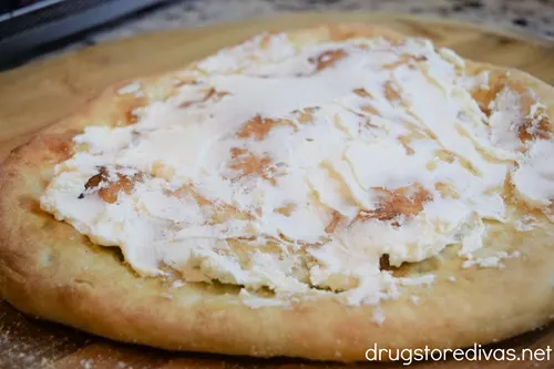 Pizza crust with goat cheese spread on top.