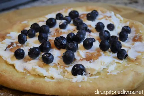 Pizza crust with goat cheese and blueberries on top.