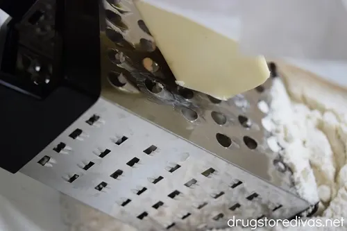 Butter being grated into a white bowl.