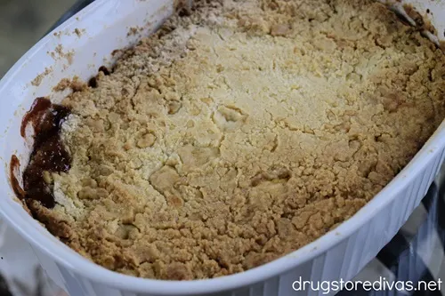 A golden brown backed peach cobbler in a white casserole pan.
