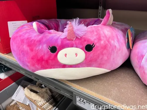 A pink unicorn Squishmallow cat bed on a shelf in a store.