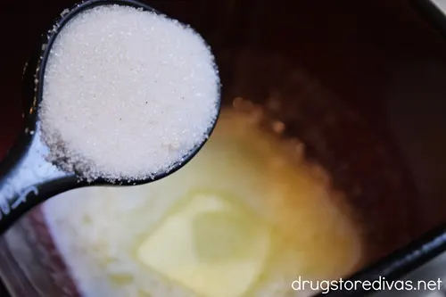 Cinnamon sugar in a measuring spoon above a small bowl of melted butter.
