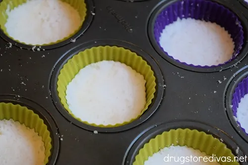 Shower steamers in yellow and purple silicone liners in a cupcake tin.