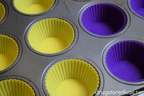 Blue and yellow silicone cupcake molds in a muffin tin.