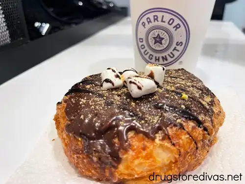 A s'mores donut with a coffee behind it that says "Parlor Doughnuts" on the cup.