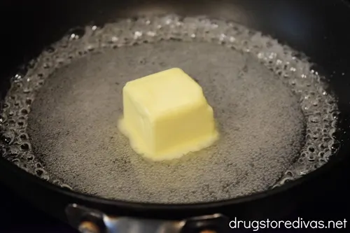 A pat of butter in the middle of liquid sugar in a pan.
